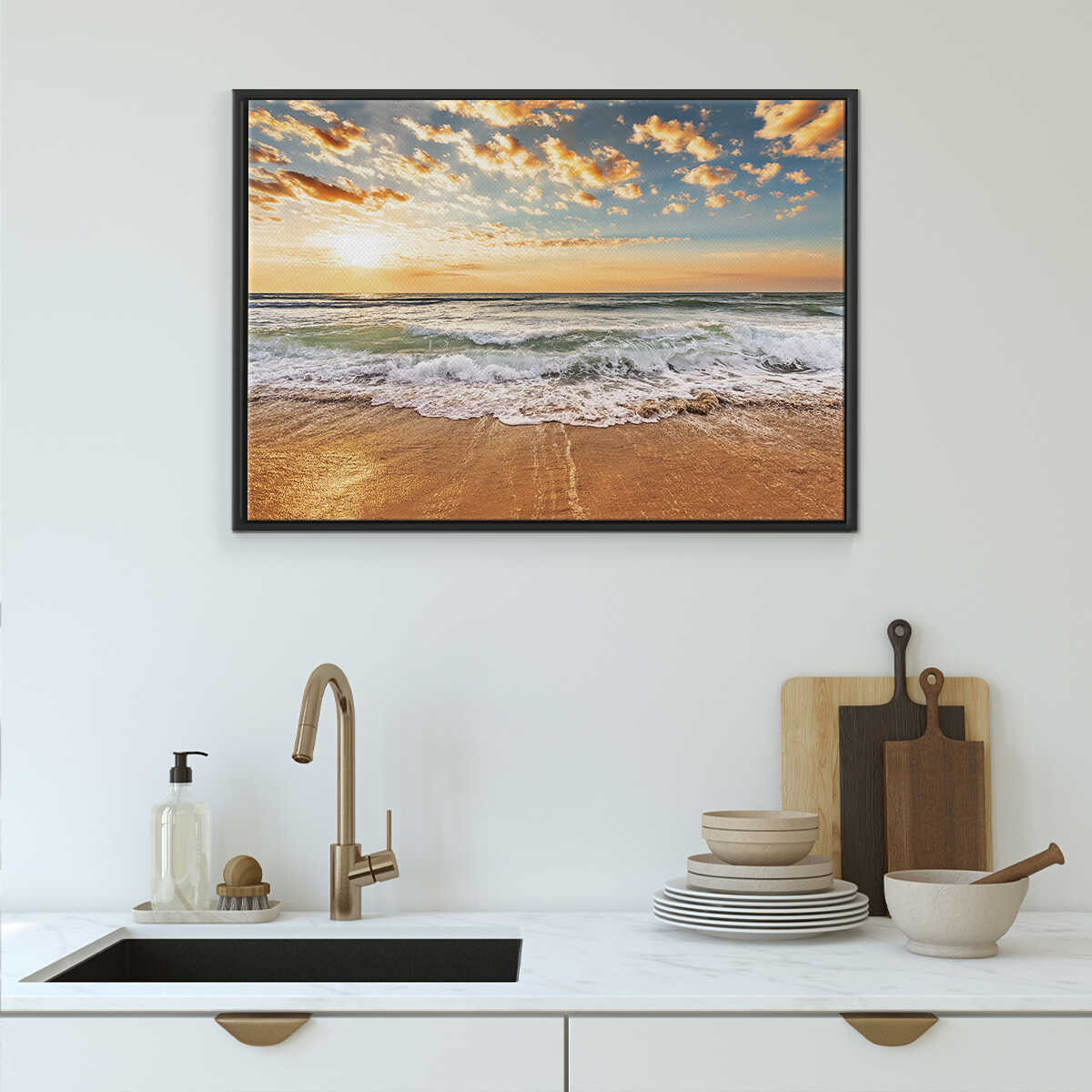 Framed beach sunset art above a kitchen sink with utensils.