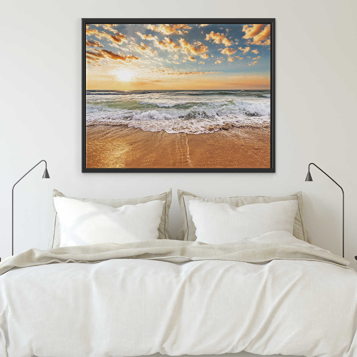 Framed beach sunset art print above a bed with white bedding.
