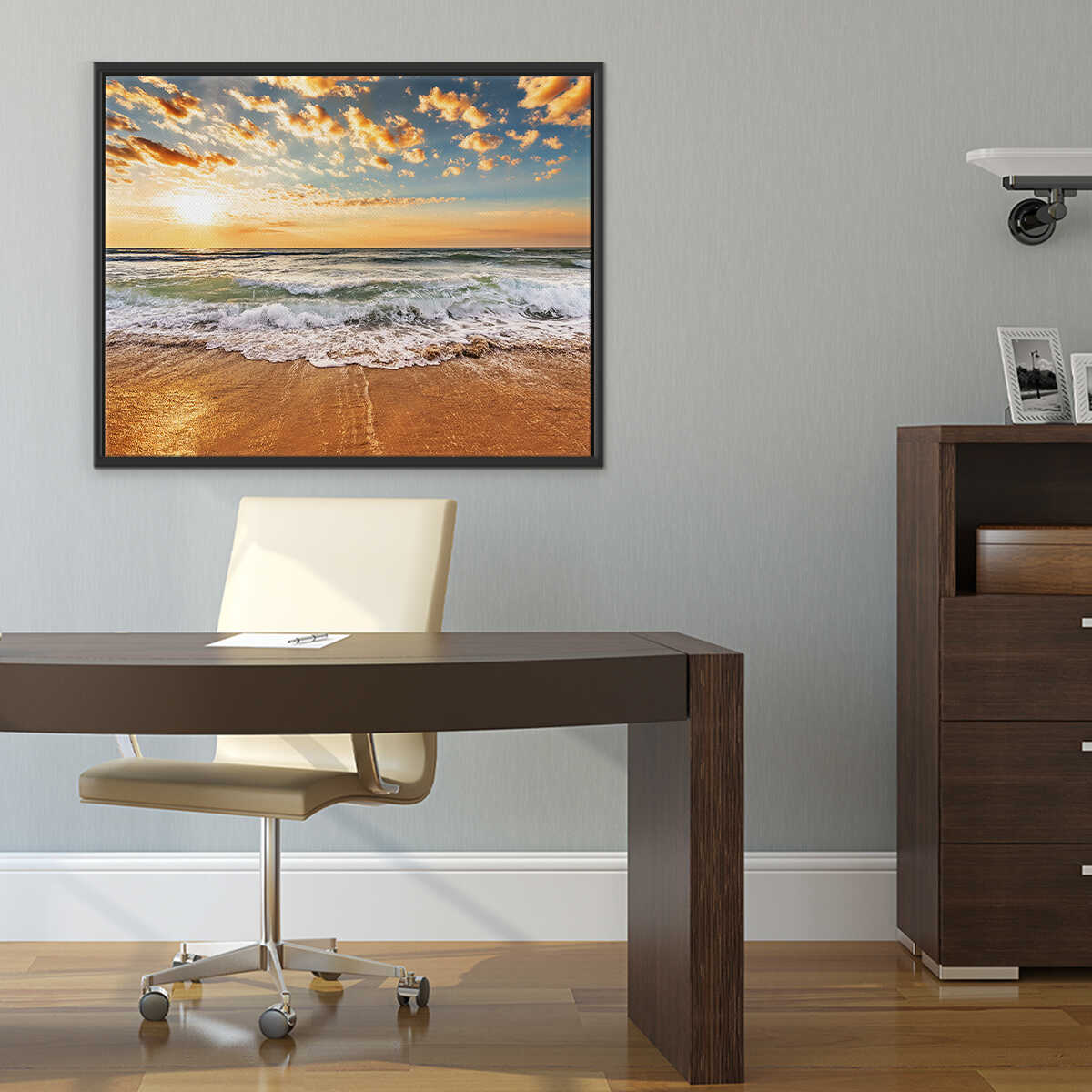 Modern office setup with a desk, chair, and framed beach scene on the wall.